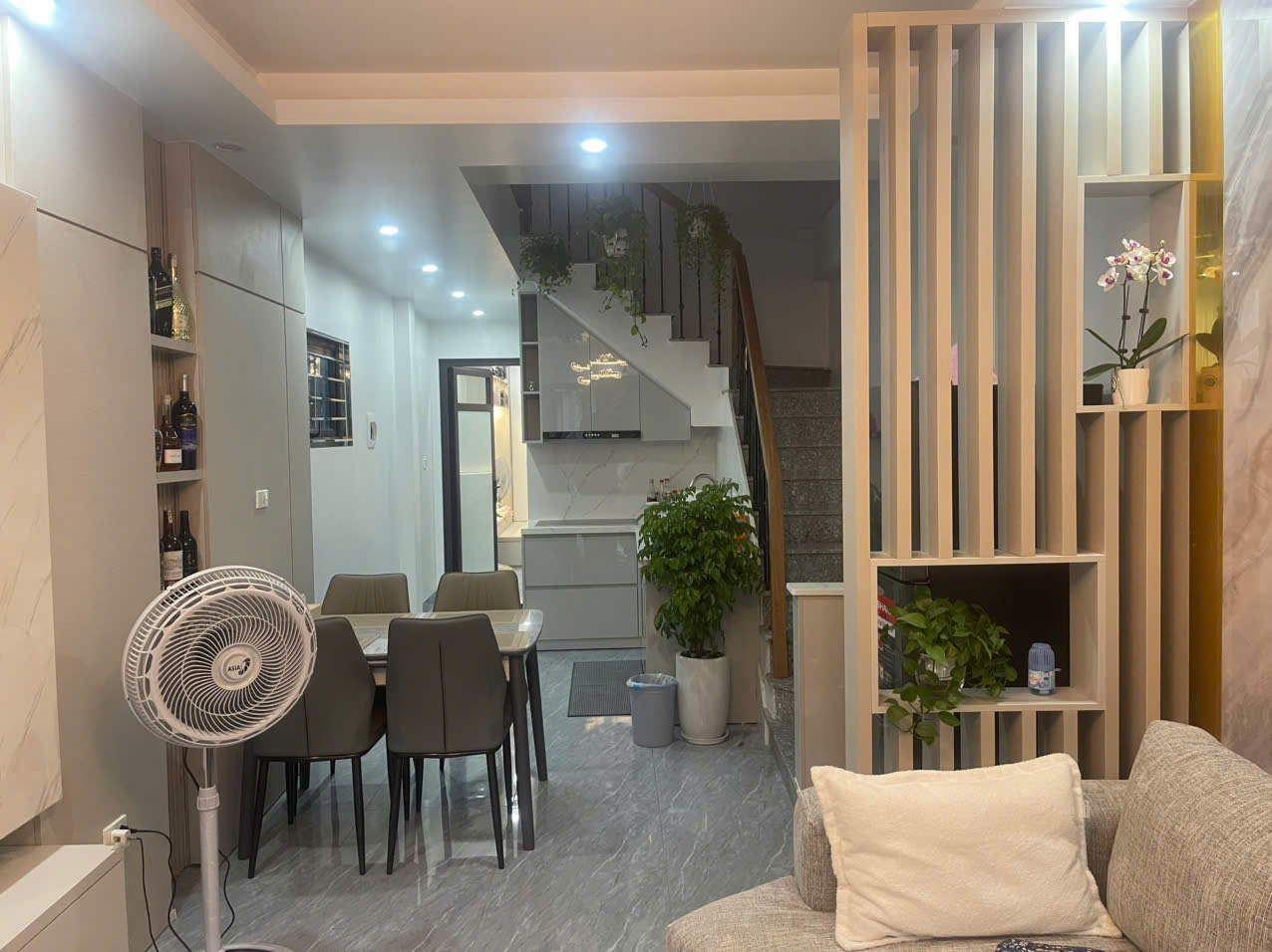 Không gian căn hộ với sofa, bàn ăn, vách trang trí và khu bếp liên thông