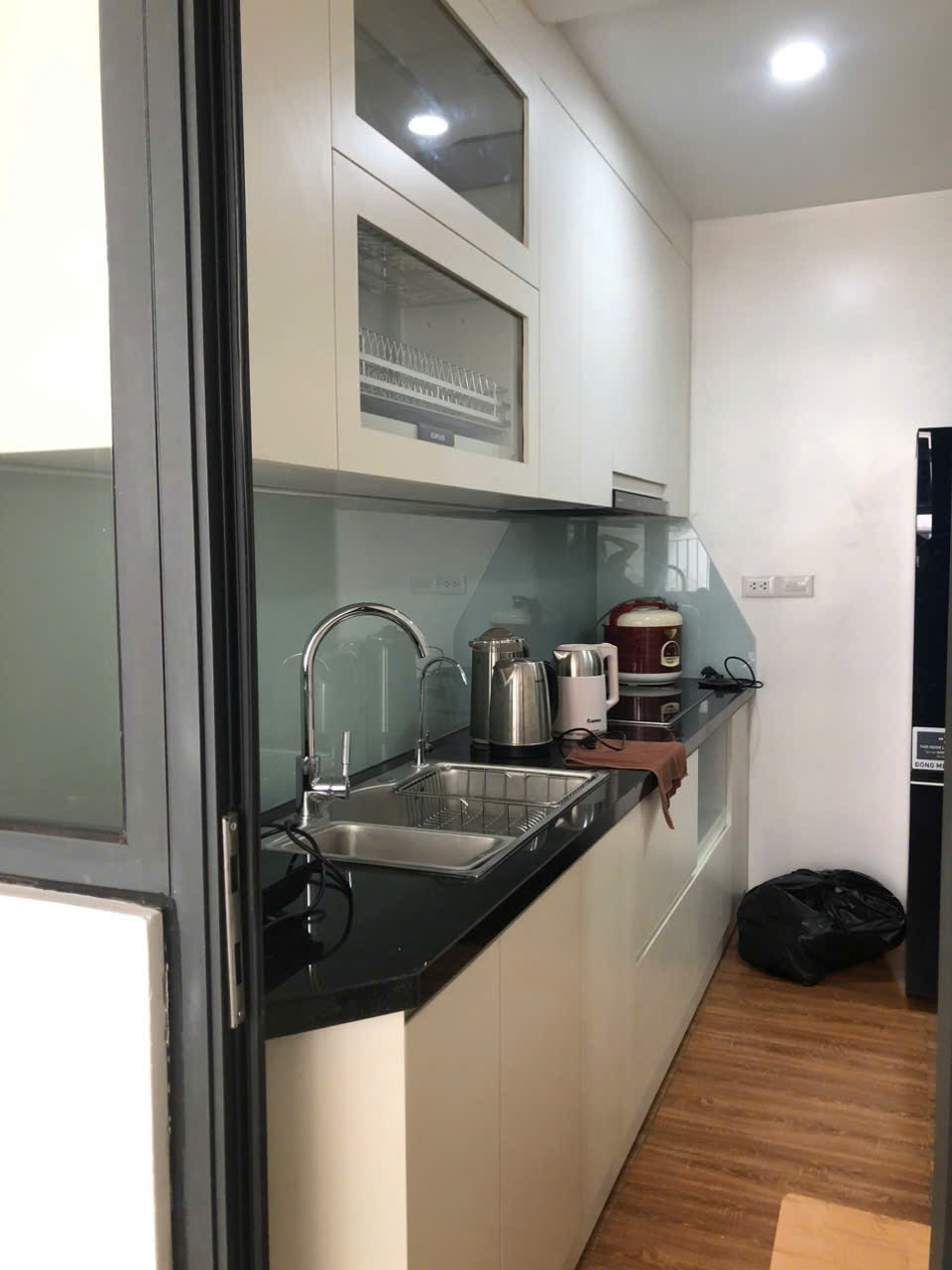 Mẫu tủ bếp compact hoàn thiện với mặt đá đen và hệ tủ treo màu sáng